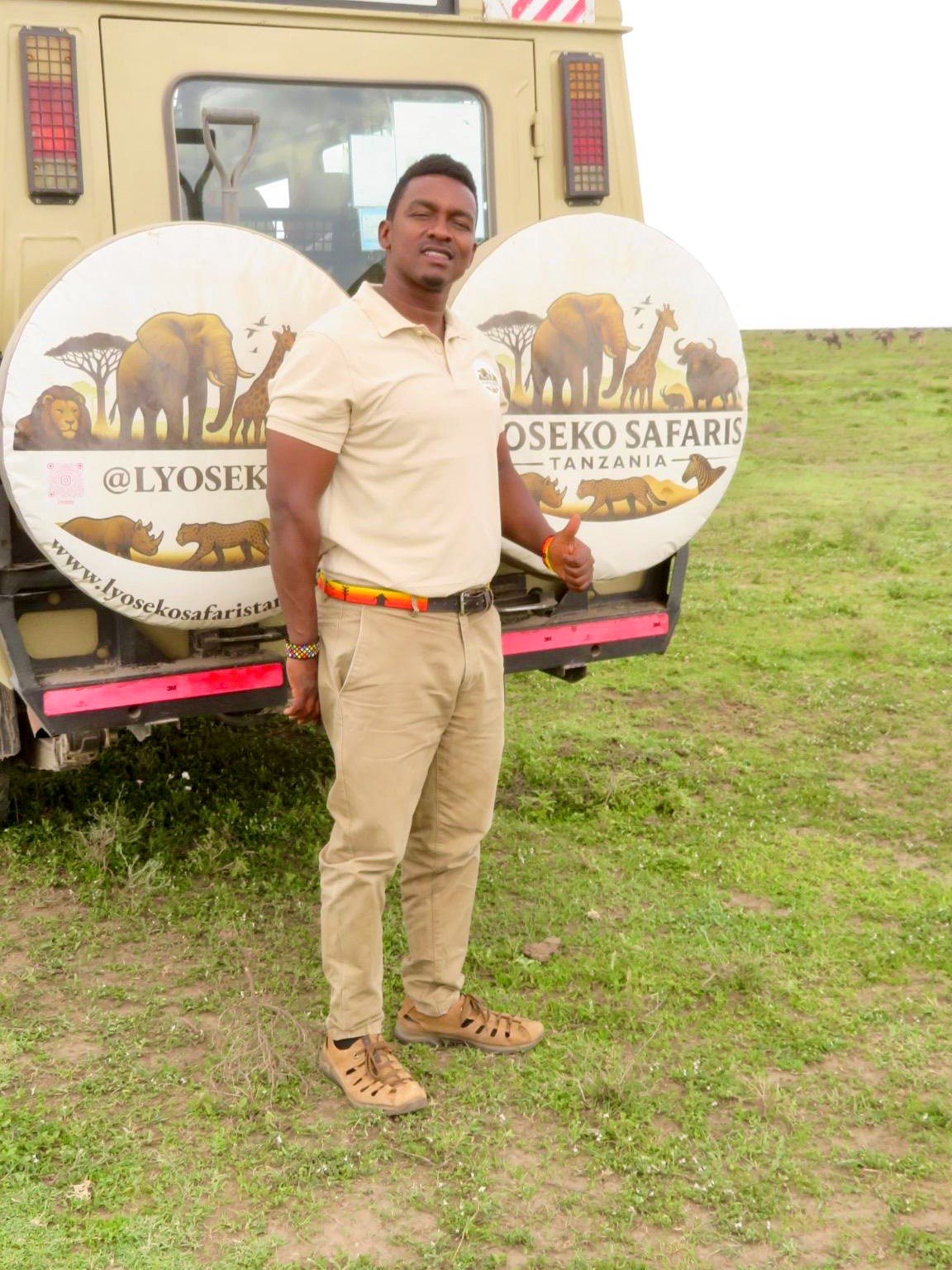 Safari guide standing in front of a safari vehicle in Tanzania